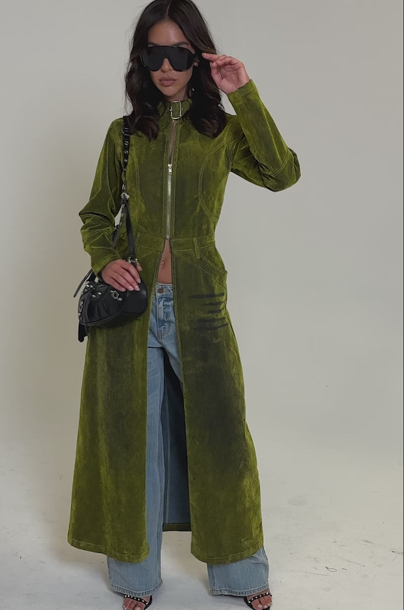 Video of woman modeling the VALERIE VELVET EFFECT TRENCH IN GREEN over blue wide-leg jeans, open-toed heels, sunglasses, and carrying a black shoulder bag