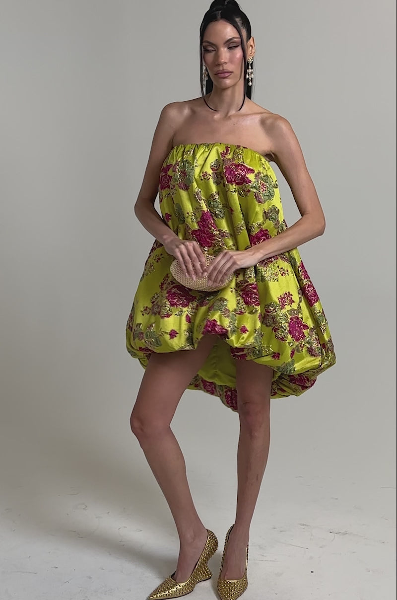 A video of a woman in the LOVER GIRL BROCADE BUBBLE DRESS, a yellow strapless mini with pink metallic floral embroidery.