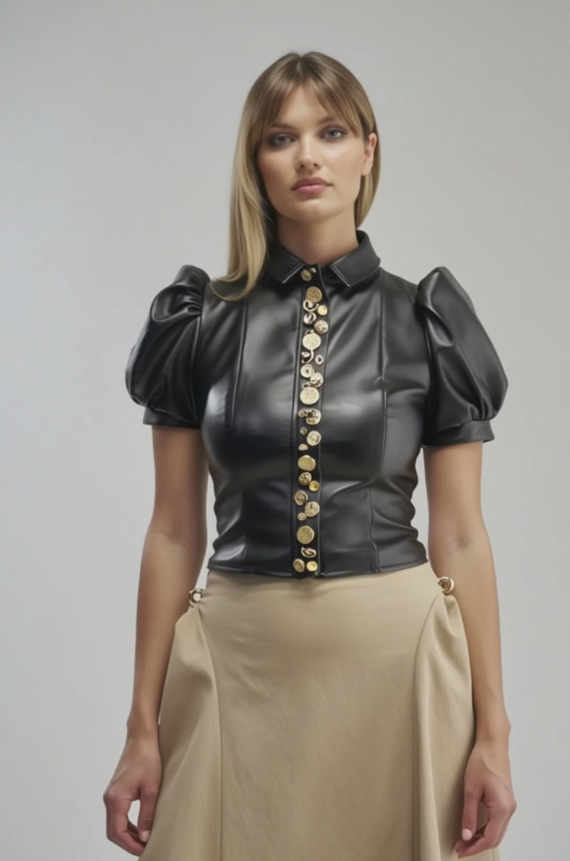 Video of a woman modeling the HOTTIE ALERT BLOUSE, a black faux leather top featuring puffed sleeves and gold buttons.