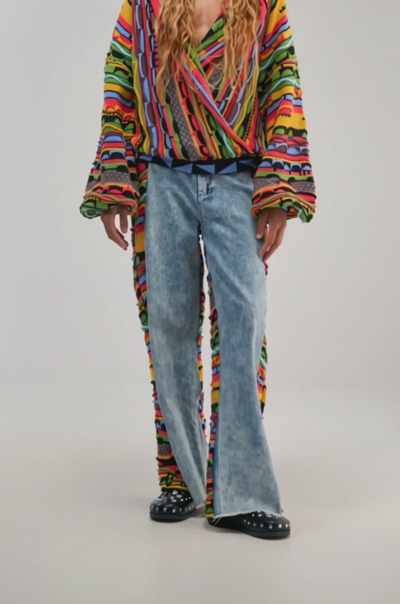 Video of a woman modeling the ONE OF ONE DENIM WITH KNIT SIDE PANELS—blue wide leg jeans accented with unique knit side details.