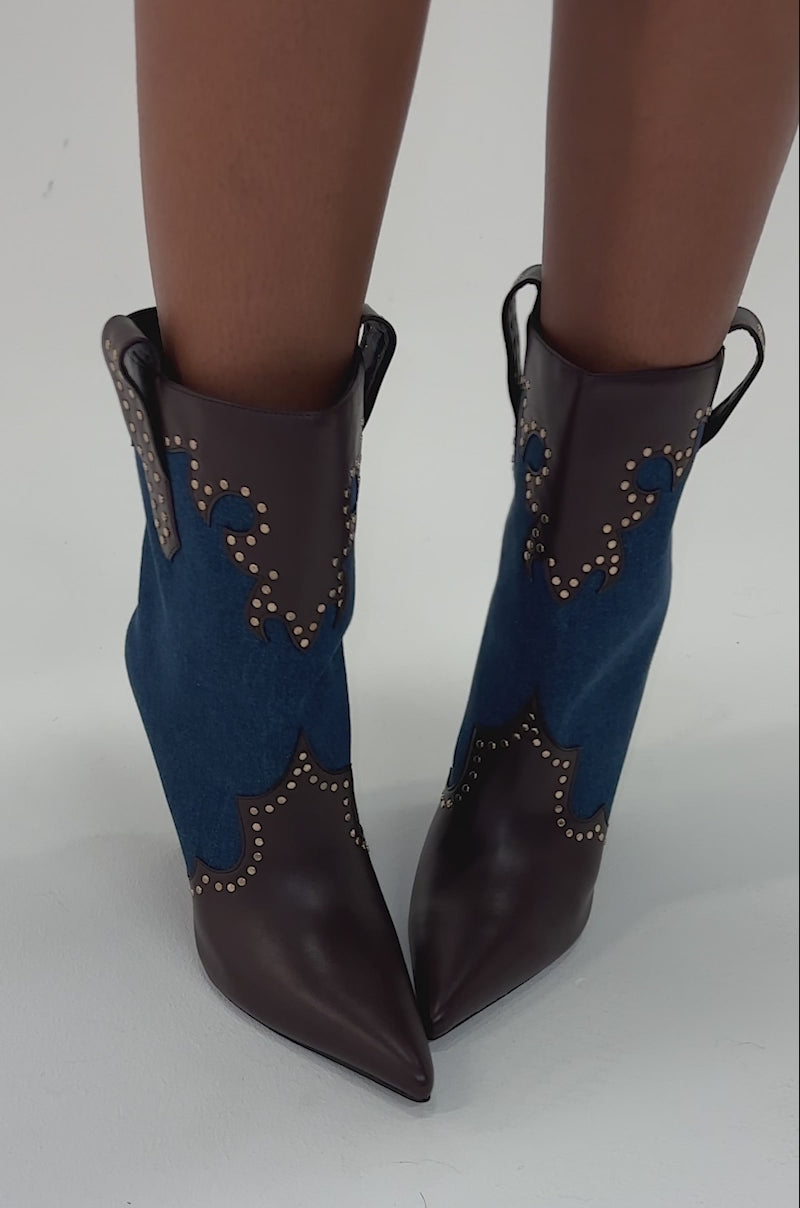Video of woman modeling the AZALEA WANG TALLULAH DENIM WEDGE WESTERN BOOTIE, featuring brown leather, blue suede accents, gold studs, a pointed toe, and a wedge heel.