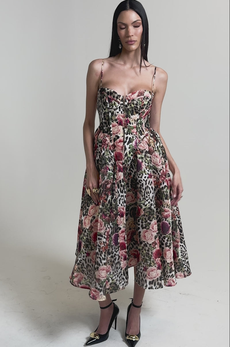 A video of a woman in the COLETTE MAXI DRESS, featuring a sleeveless leopard print design with thin straps and a fitted corset bodice. 