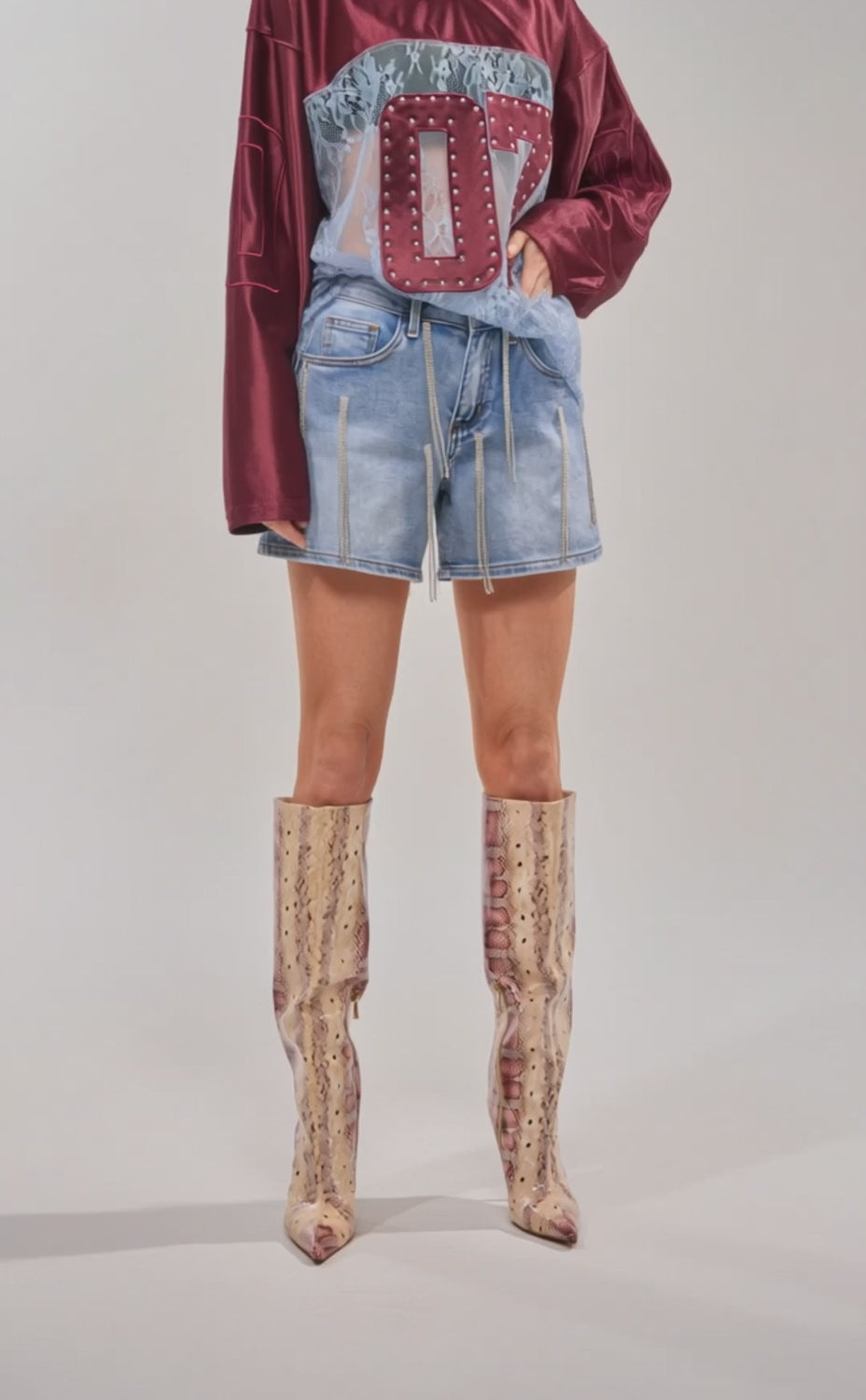 Video of woman modeling the DRIP CITY DENIM SHORT blue high-waist zipper-detailed shorts, and knee-high pointed-toe snakeskin boots against a light background.