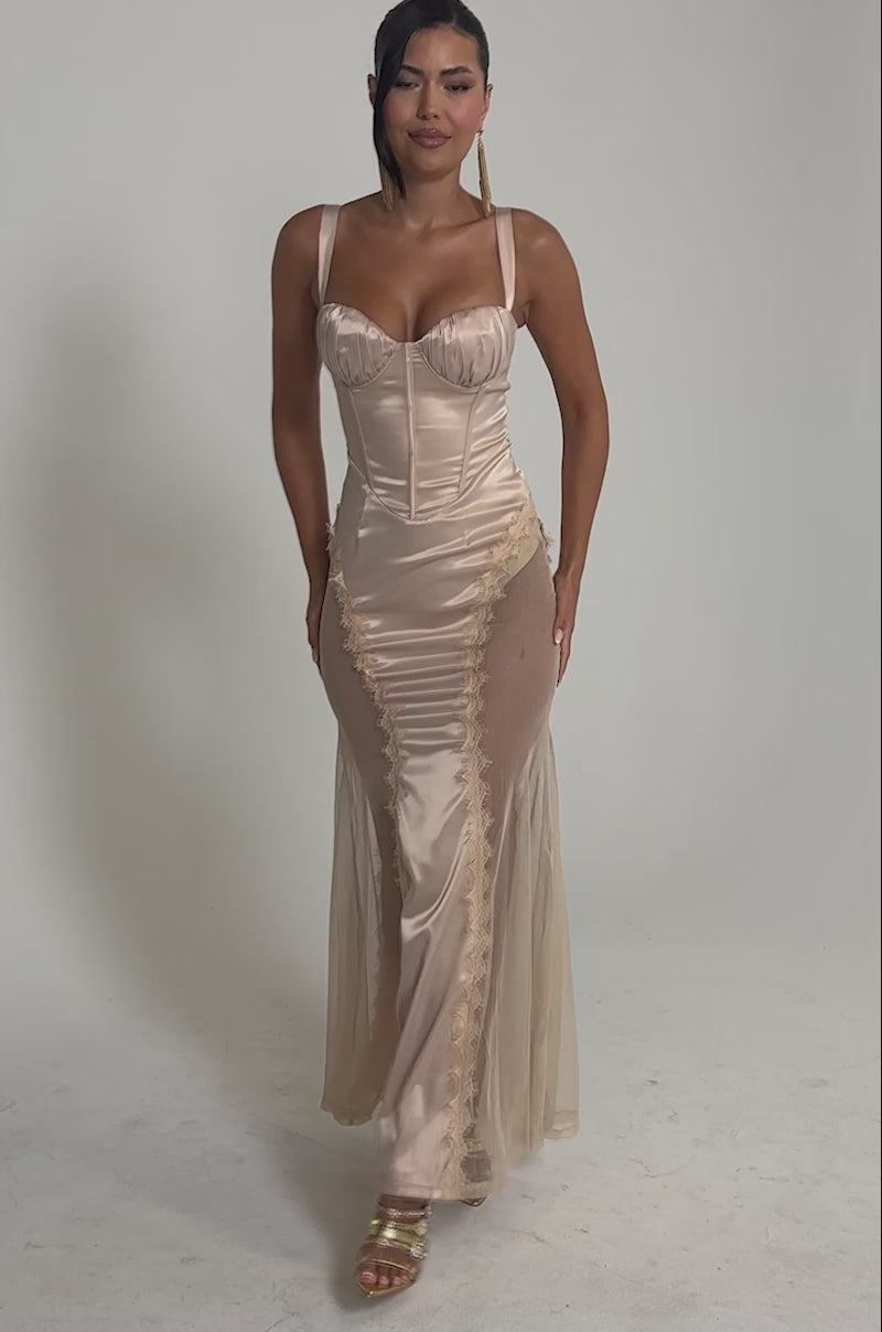Video of woman modeling the FIND ME AT MIDNIGHT SATIN MAXI DRESS IN IVORY, which features a fitted, strapless silhouette with a corset-inspired bodice and mesh side panels. She accessorizes with gold earrings and high-heeled sandals