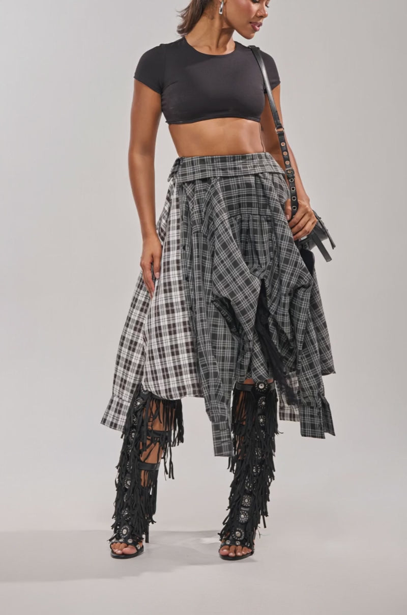 A video of a woman in the FALL VIBES PLAID MIDI SKIRT, black fringe heeled boots, and a small black bag.