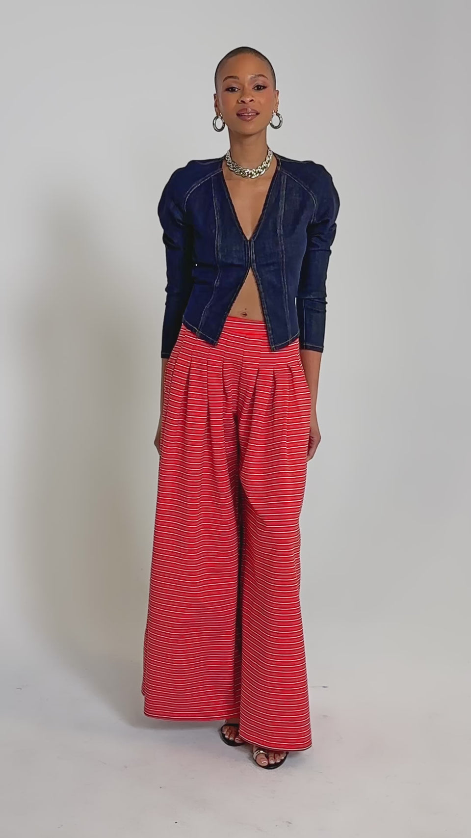 Video of woman modeling the SILVER COAST STRIPE TROUSER featuring a high-rise waist and colorful horizontal stripes. Hoop earrings and a necklace complete the look.