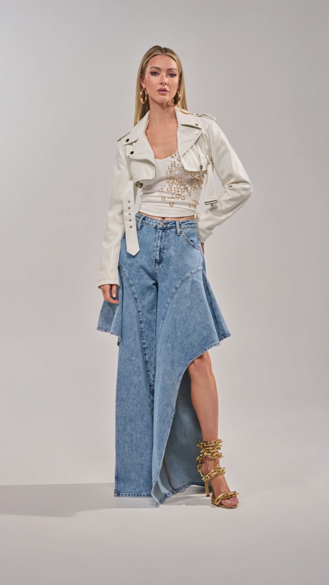 Video of woman modeling the Check It Out Relaxed Denim open-leg jeans, paired with a white cropped jacket, embellished top, gold strappy heels, and gold jewelry.