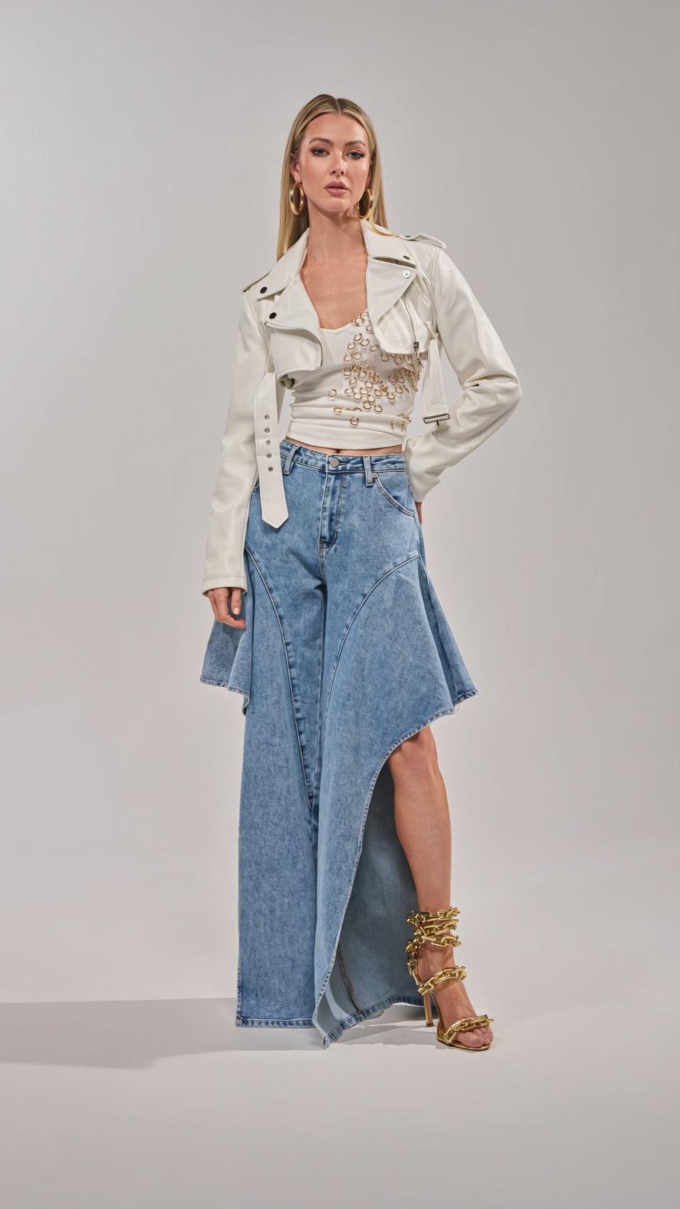 Video of woman modeling the Check It Out Relaxed Denim open-leg jeans, paired with a white cropped jacket, embellished top, gold strappy heels, and gold jewelry.