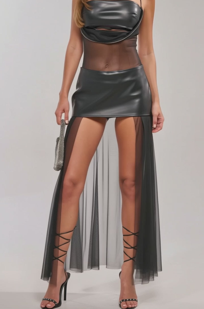 Video of woman TRUE ICON CUT OUT MINI DRESS, a black faux leather mesh-paneled dress with a cowl neckline and high slits. She finishes her bold look with a small silver handbag and lace-up high heel sandals.