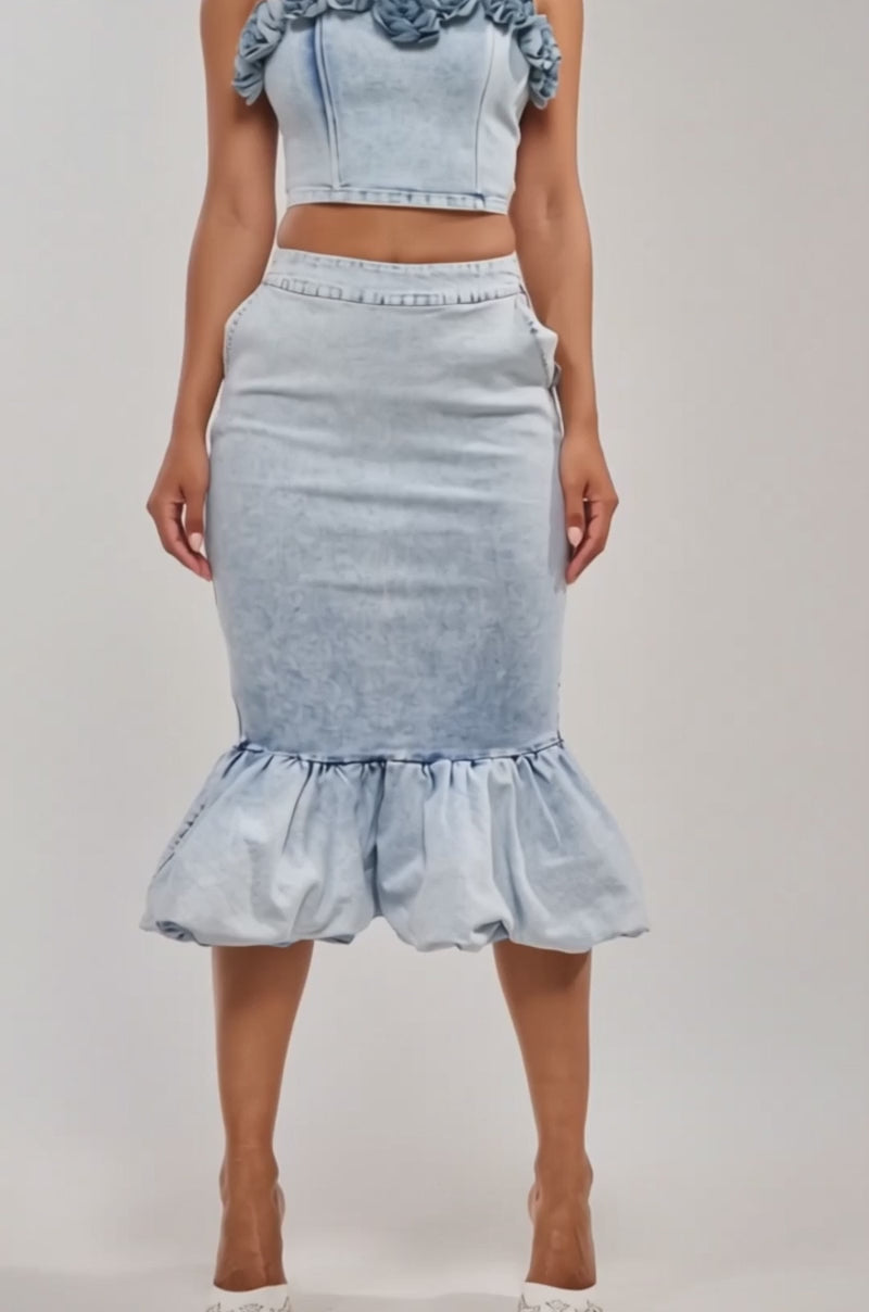 Video of woman modeling the LOVE ME LIKE THAT FLOWER CORSET, a light denim top with floral neckline detail, paired with a matching high-waisted skirt.