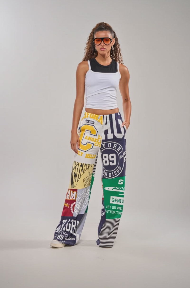 Video of woman modeling the GAME TIME PATCHWORK JOGGER featuring colorful streetwear-inspired designs with bold logos, numbers, and graphic text.