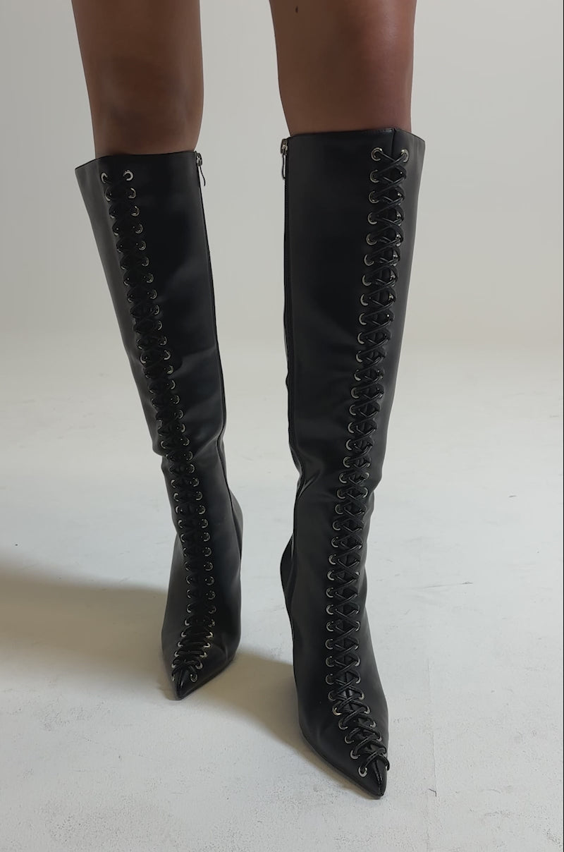 A video of a person wearing a textured black mini skirt and AZALEA WANG THAUMUS BLACK LACE UP WEDGE BOOTS, standing against a neutral background.
