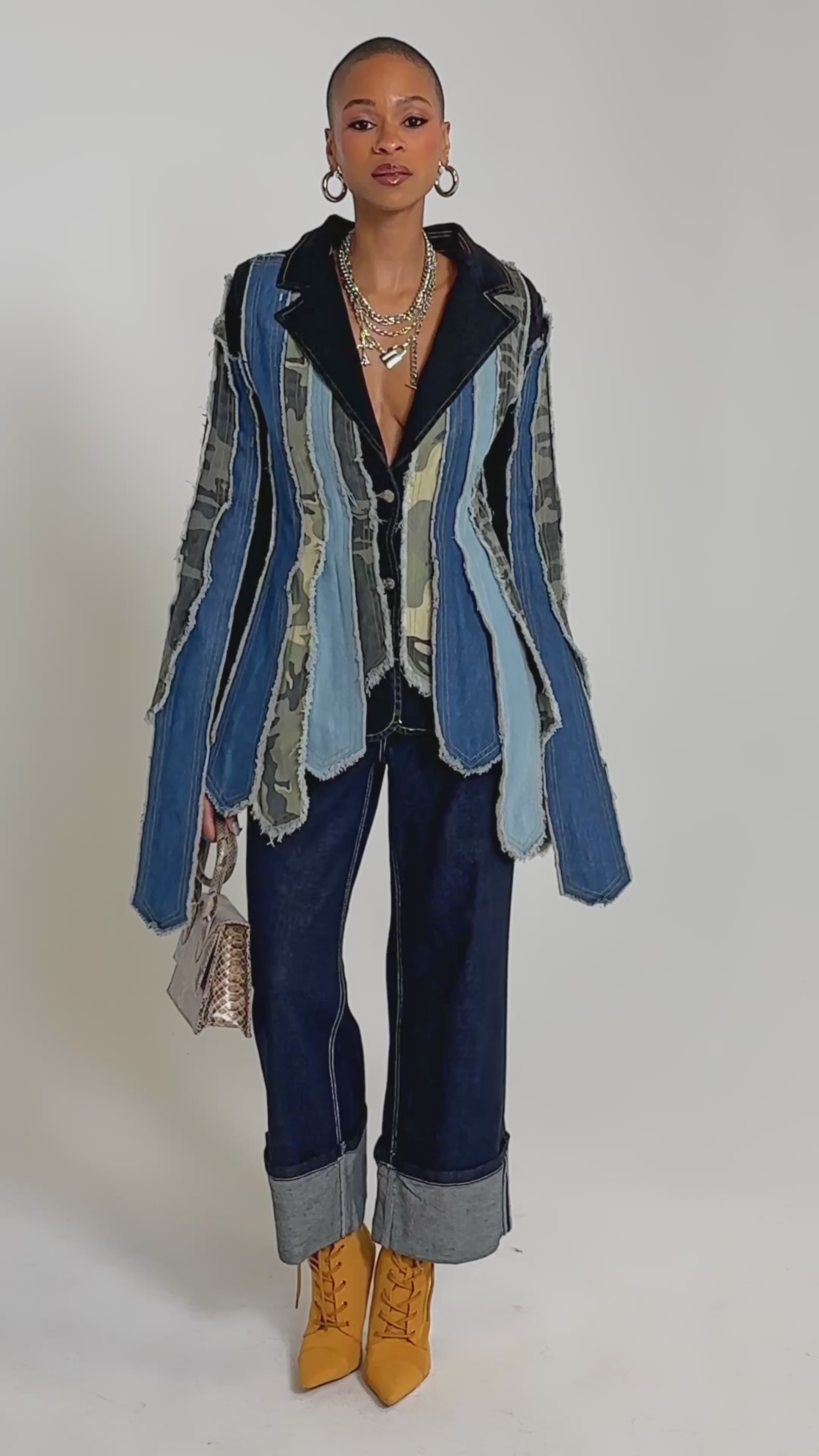Video of woman modeling the HERE FOR IT PATCHWORK BLAZER, crafted from distressed camouflage denim, styled with dark pants, hoop earrings, layered necklaces, and a textured handbag.