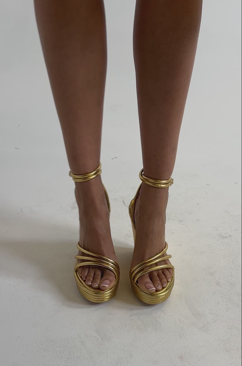 A video of a person wearing the AZALEA WANG AVENY Gold Strap Round Toe Wedge Sandals stands against a plain light background.