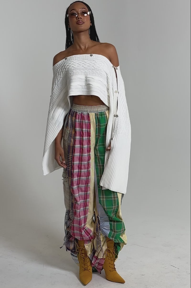 A video of a woman  in the MIXED PLAIDS JOGGERs, a white off-the-shoulder top, mustard yellow lace-up boots, and pink-tinted sunglasses.