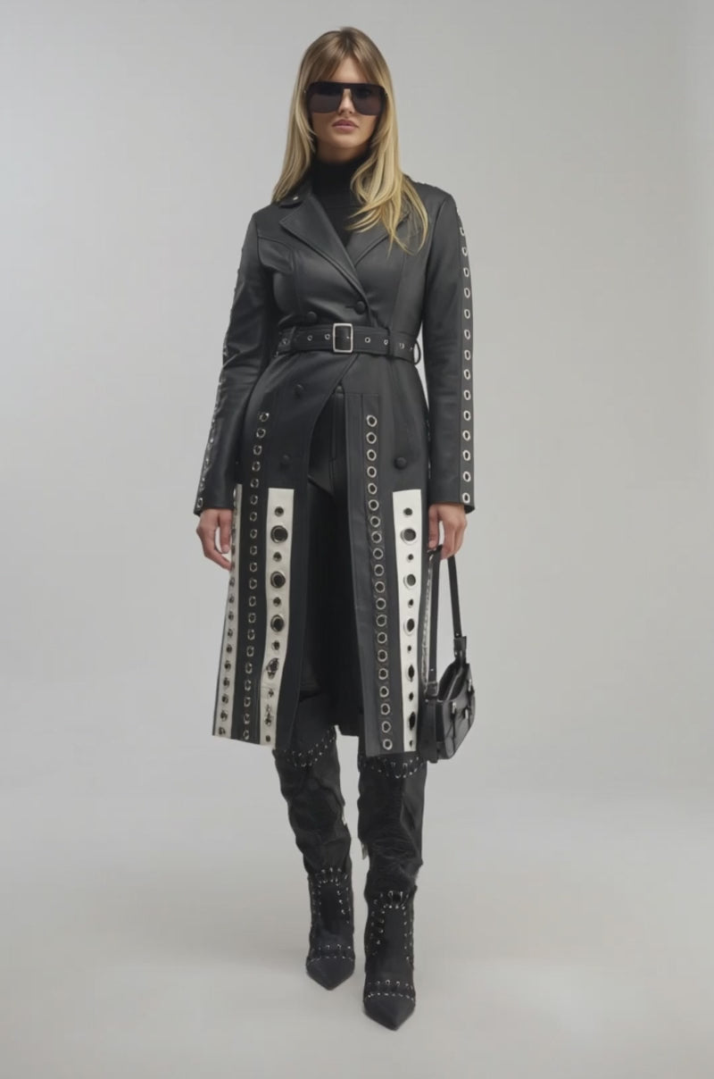 Video of a woman modeling the FIGURE IT OUT GROMMET TRENCH—a black faux leather trench detailed with silver grommets.