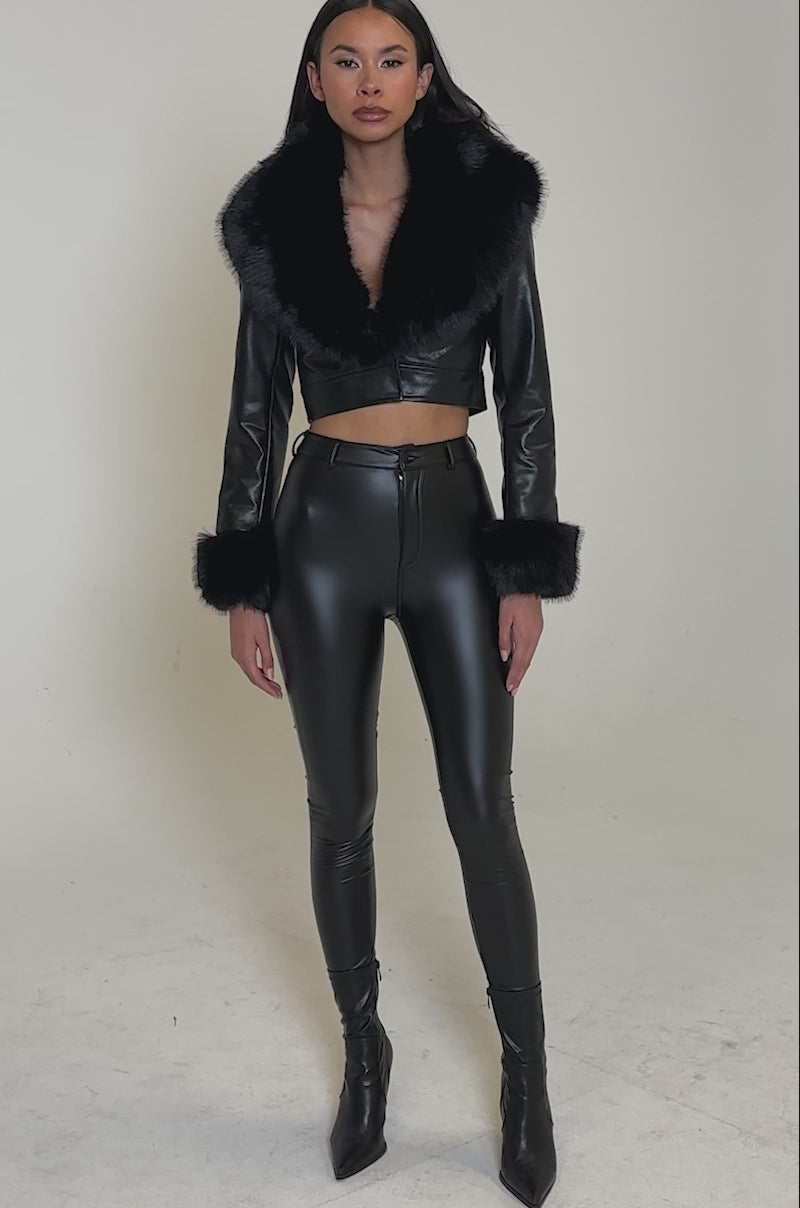 Video of woman modeling the GISELE CROP MOTO BLAZER with high-waisted black leather pants, posing against a plain, neutral background.
