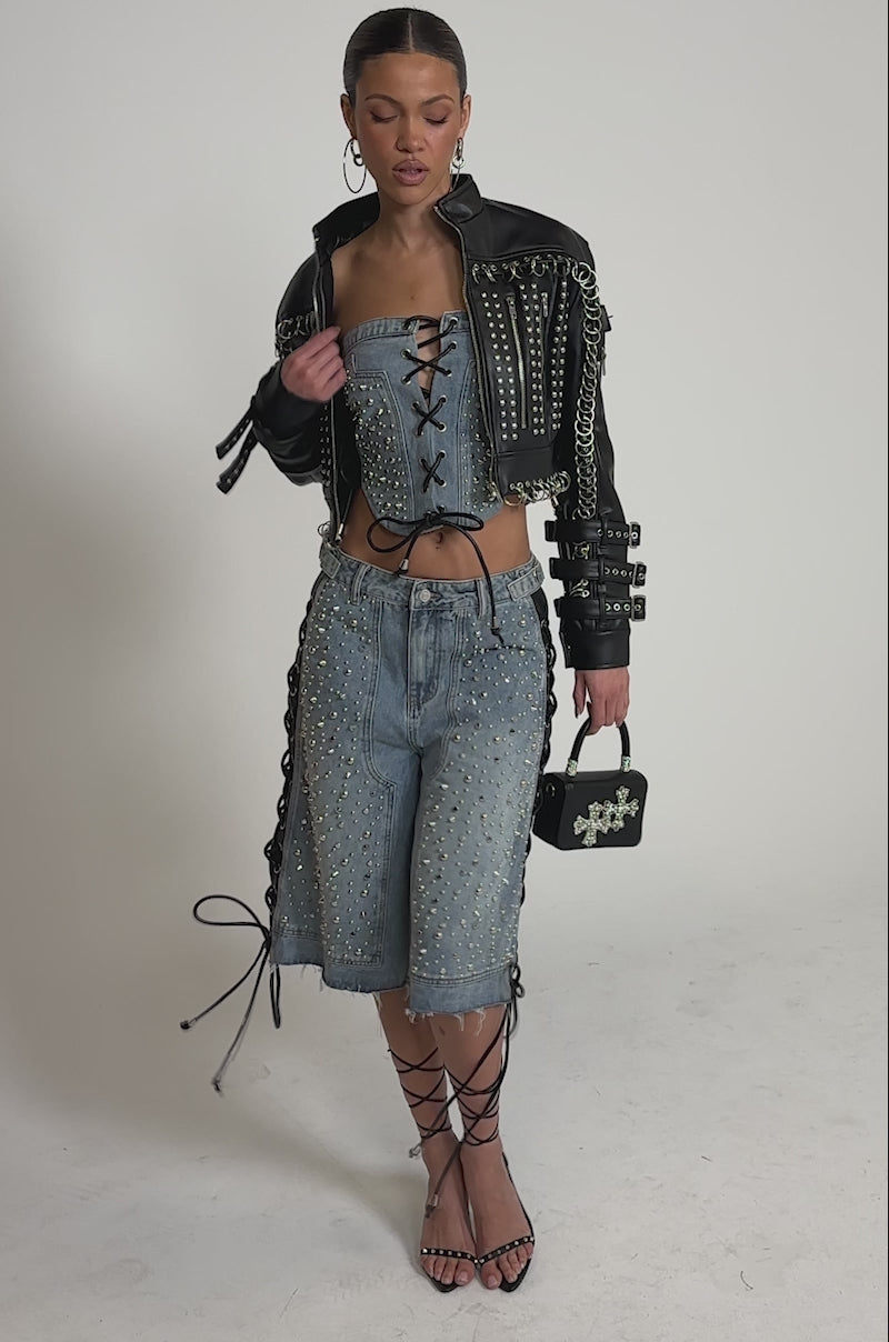 A video of a woman in the CHOPPER STUDDED MOTO jacket, lace-up denim bustier, and knee-length studded denim shorts. 