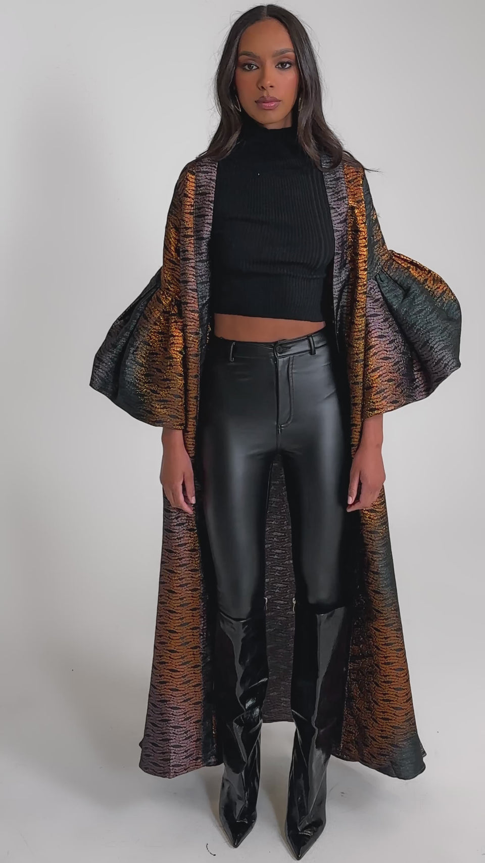Video of woman modeling the FLORENCE BROCADE PUFF SLEEVE DUSTER over a black crop top and shiny black pants tucked into pointed boots.