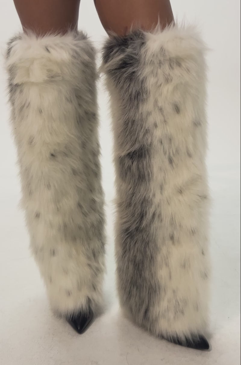 Video of woman modeling the AZALEA WANG LANGLEYE CREAM MULTI SNOW LEOPARD THIGH HIGH FUR BOOTS—white with gray spots and fluffy, covering black pointed shoes, against a plain background.