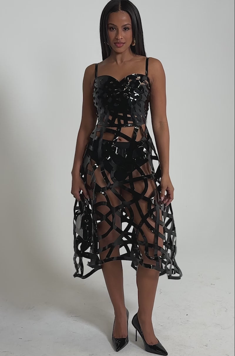 A video of a woman in the CAUGHT YOU SLIPPING CAGED MIDI DRESS, featuring geometric cage-style cutouts.