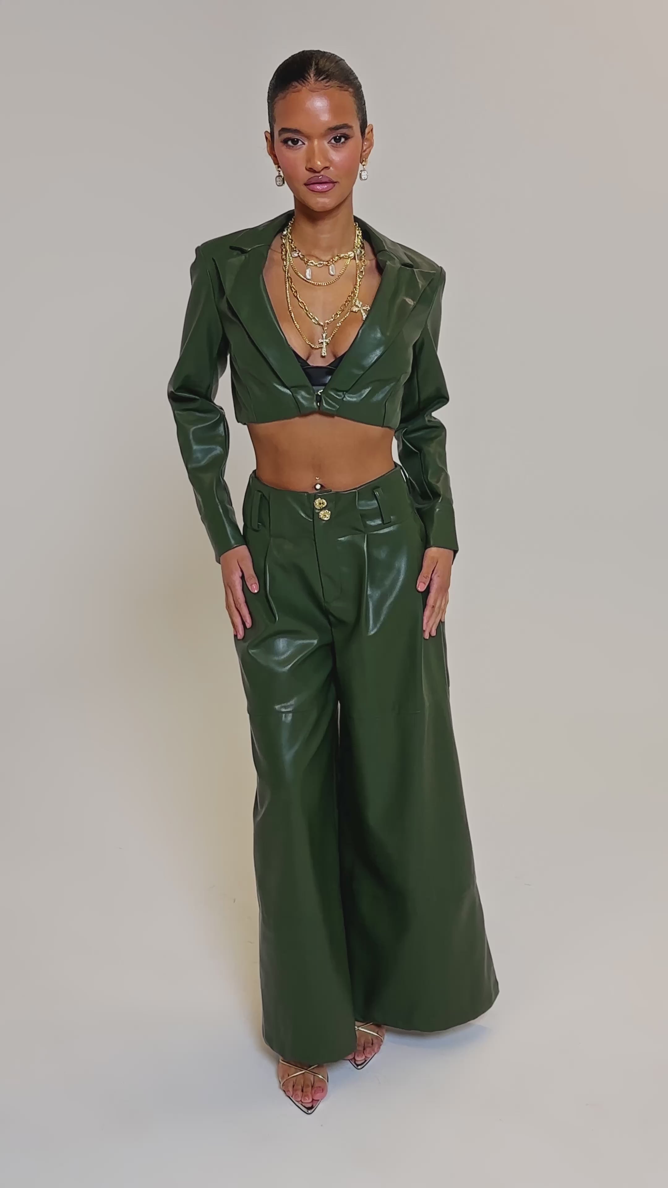 Video of woman modeling the REMEMBER YOU WIDE LEG TROUSER and a matching olive green faux leather cropped jacket, styled with layered necklaces and strappy heels against a plain light background.