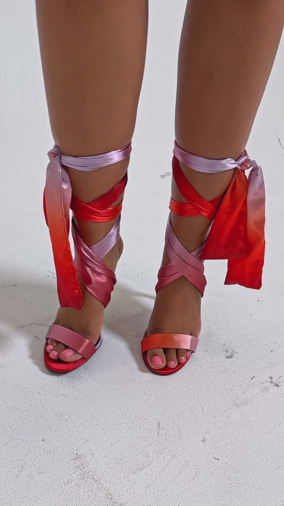 A video of a person wearing a pink ribbed skirt and AZALEA WANG ELZON ORANGE SATIN STRAPPY SANDALS.