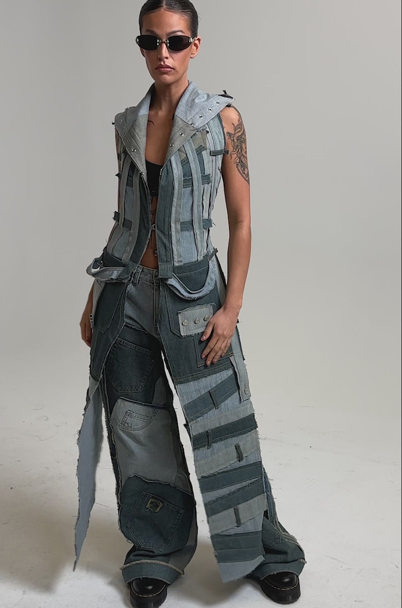 Video of woman modeling the ALL THAT DISTRESSED HOODED TOP—a patchwork denim sleeveless hoodie with frayed edges, visible stitching, and various blue shades—matched with wide-leg pants.
