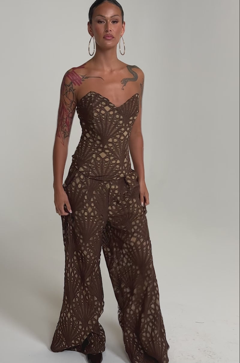 A video of a person wearing the CLAIRE EYELET PALAZZO PANT, featuring a strapless brown lace bodice and wide-leg fit.