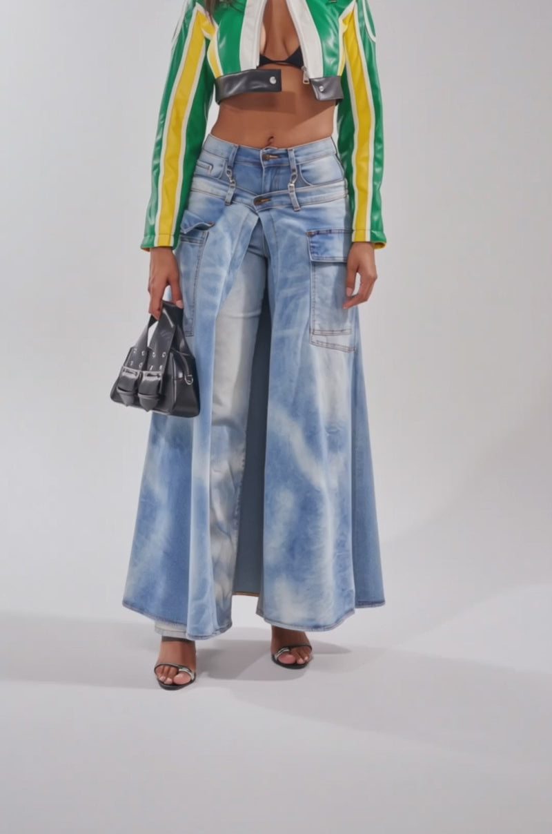 A video of a woman in the BIG FAN CROPPED MOTO jacket, glasses, wide-leg light blue jeans, black sandals, and a small black handbag.