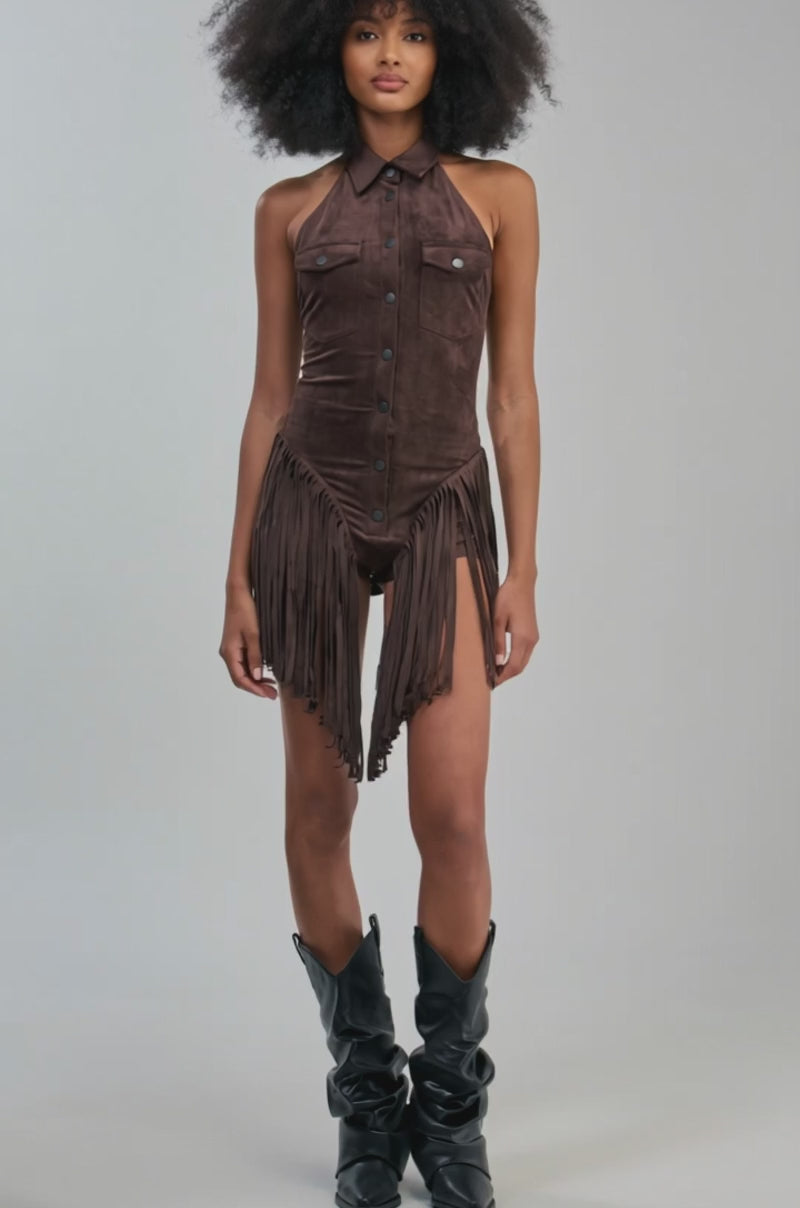 Video of a woman modeling the FLIRTY FRINGE SUEDE ROMPER—a sleeveless, brown western-style romper featuring a collar, button-down front, chest pockets, and fringe detailing at the hem.