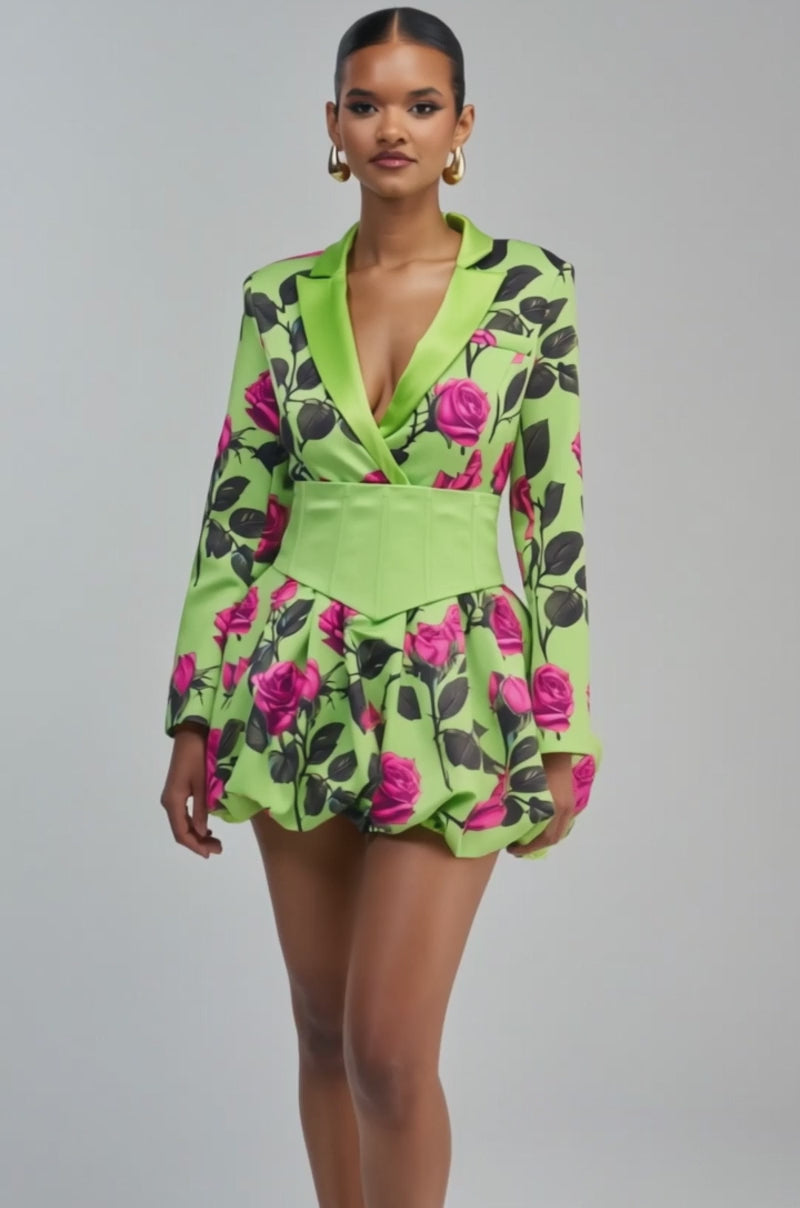 Video of a woman modeling the PAINTING THE ROSES GREEN BUBBLE MINI DRESS WITH CORSET, which features a rose graphic design in a green blazer style with pink rose patterns and a wide light green belt. 