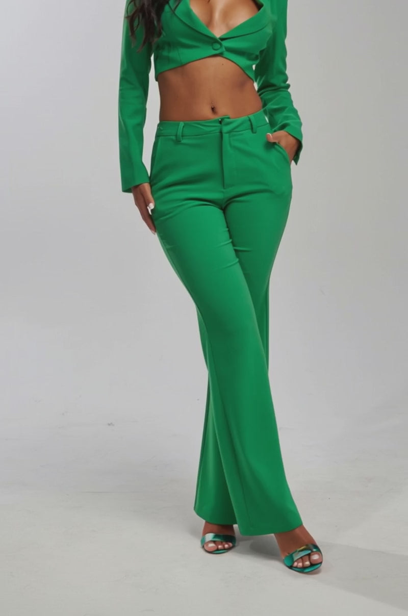 Video of woman modeling the JUST YOUR LUCK FLARE TROUSER IN GREEN, styled with matching high-heeled sandals and a coordinating green blazer. The photo is cropped from the torso down.