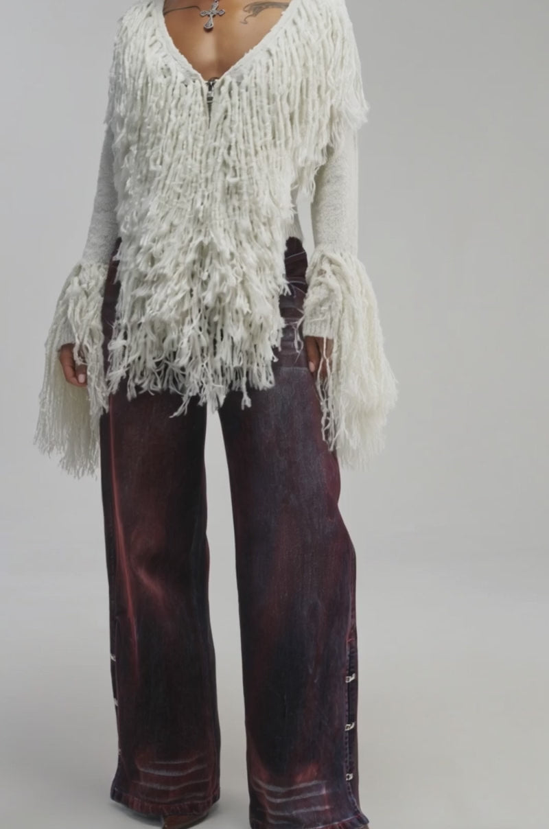 Video of a woman modeling the AT YOUR BEST FRINGE CARDIGAN—a textured, off-white statement piece with fringed details and flared sleeves.