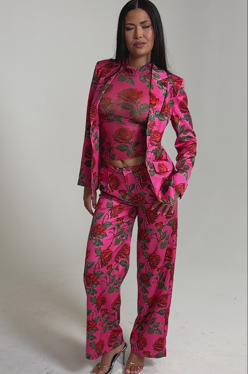 A video of a woman in the DOZEN ROSES SATIN PANT IN FUCHSIA set against a plain light background.