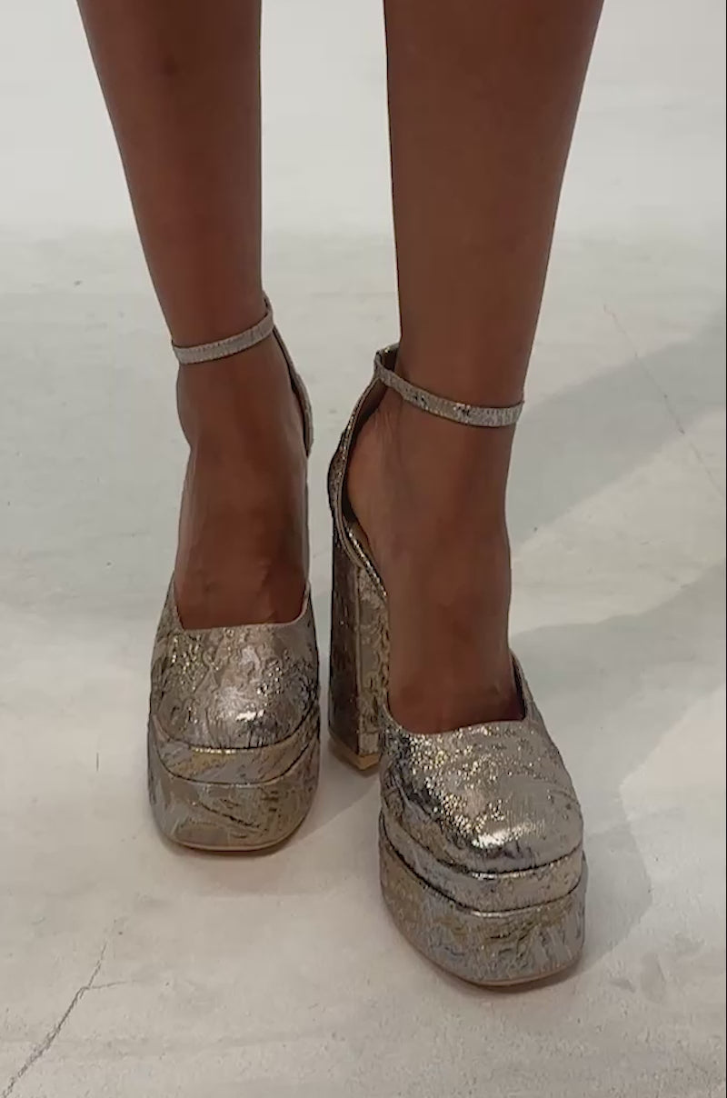 Video of woman modeling the AZALEA WANG ZIPPHORA GOLD MULTI BROCADE PLATFORM PUMP, metallic platform heels that shimmer brilliantly from every angle.