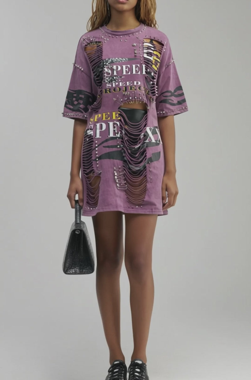 Video of a woman modeling the NEVER TOO MUCH DISTRESSED OVERSIZED TEE IN PLUM—an edgy streetwear dress featuring “SPEED” text, zebra and leopard prints, studs, safety pin accents, and shredded details.