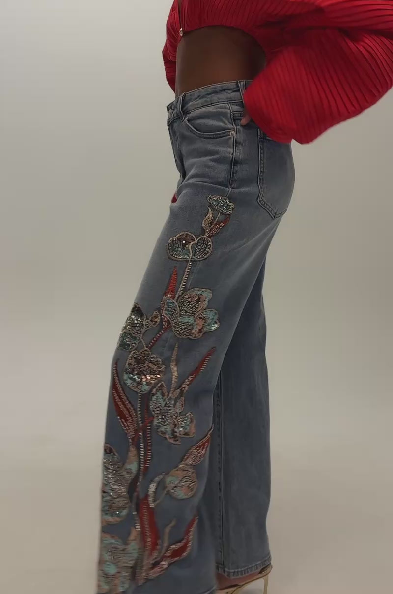 Video of a woman modeling the PRETTY LIKE ME EMBELLISHED DENIM high-rise, wide-leg jeans with floral embroidery.