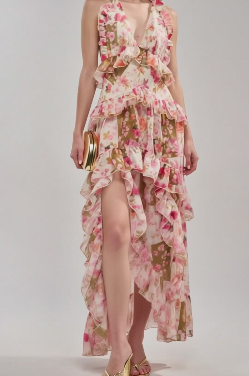 Video of woman modeling the SUMMER STROLL FLORAL CHIFFON MAXI DRESS, featuring pink floral chiffon, ruffled layers, a deep V-neck, and a high slit. 