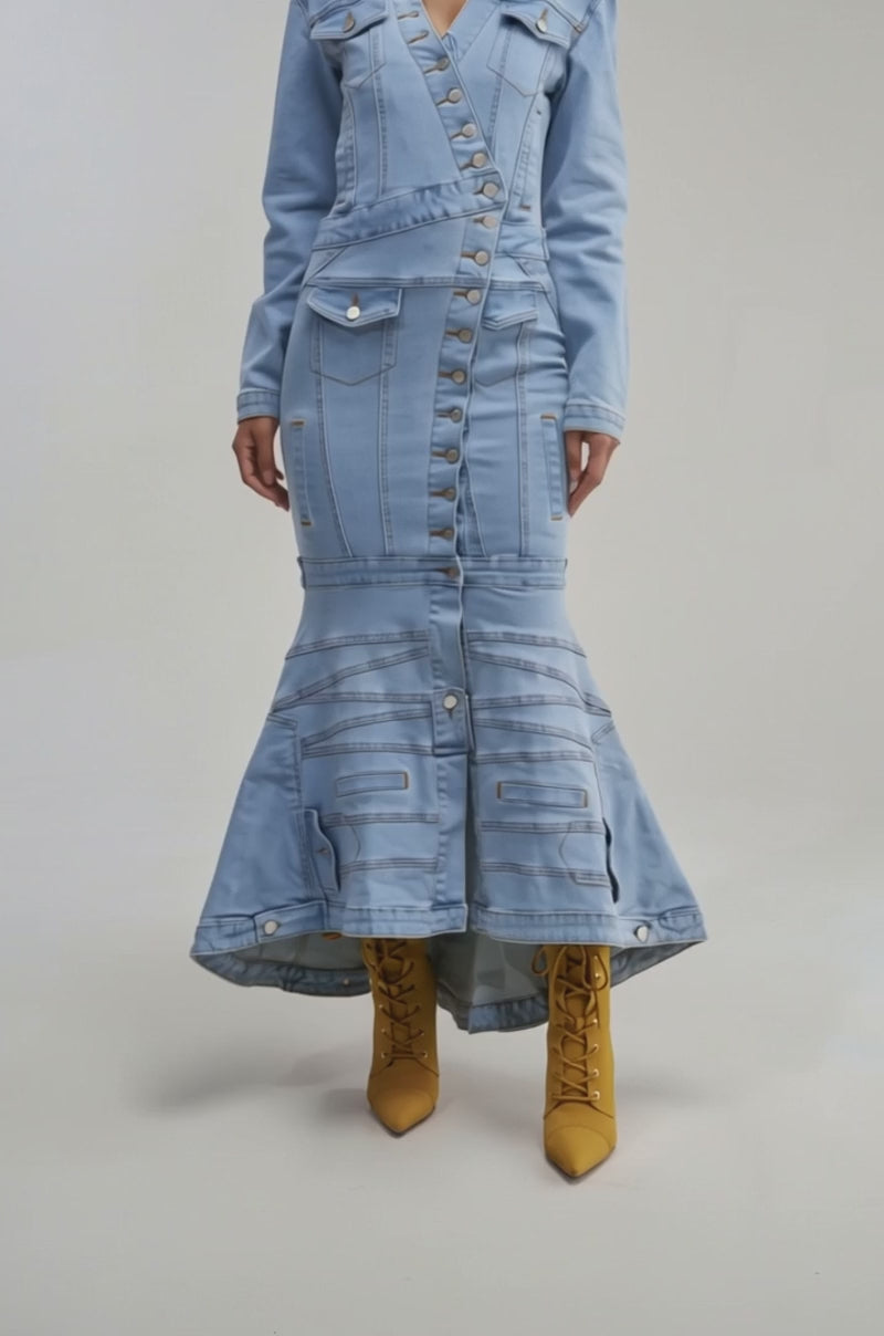 A video of a woman wearing the TRAPEZE BUTTON DOWN DENIM MAXI DRESS in a light wash with long sleeves, button details, and a mermaid skirt. 
