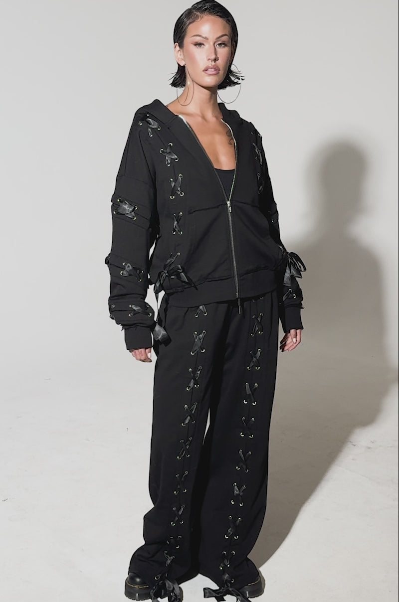 Video of woman modeling the ALL LACED UP HOODIE, showcasing its distinctive lace-up paneling on the sleeves
