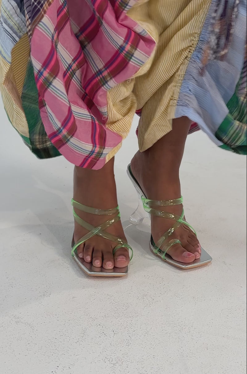 A video of a person wearing a colorful patchwork skirt with gathered details and the AZALEA WANG LEMUEL GREEN AND SILVER WEDGE SANDAL.