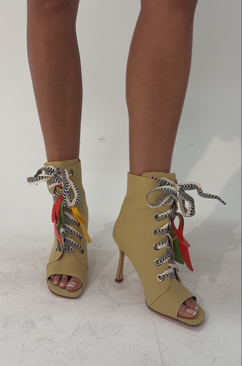 A video of a person wearing the AZALEA WANG ROVEA KHAKI LACE UP STILETTO BOOTIE, featuring multicolored laces and red tags.