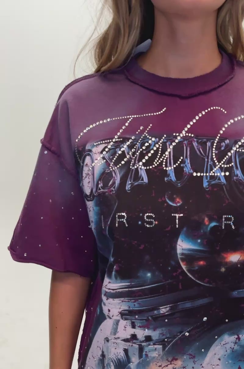 Video of a woman modeling the FIRST ROW INTERSTELLAR RHINESTONE TEE IN PLUM featuring an oversized galaxy graphic.