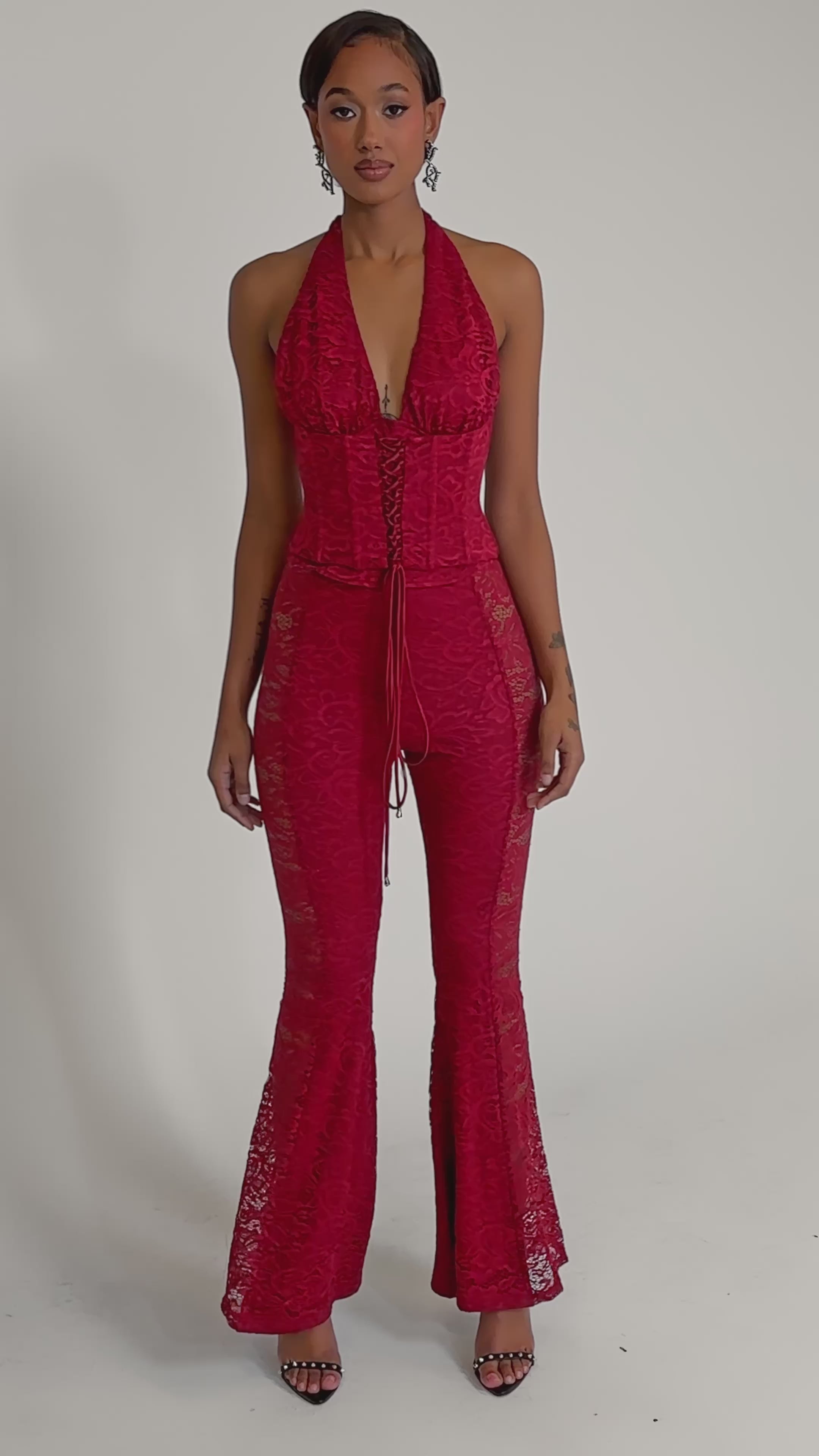 A video of a woman wearing the LOVE BOMB LACE CORSET, styled with fitted bodice, flared legs, and strappy high-heeled sandals.