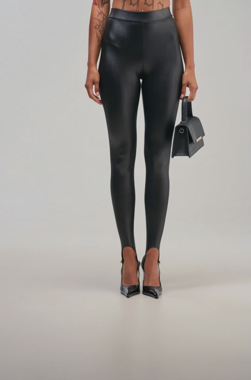 Video of a woman modeling the LOVE IS IN THE AIR STIRRUP LEGGING in black, styled with black pointed heels and holding a small tortoiseshell-patterned clutch.