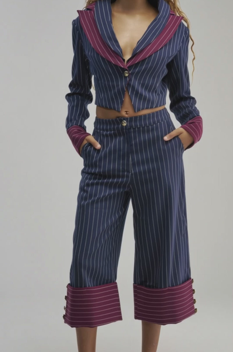 Video of a woman modeling the NEVER BETTER PINSTRIPE BLAZER—a navy blue pinstripe cropped piece featuring maroon collar and cuffs.