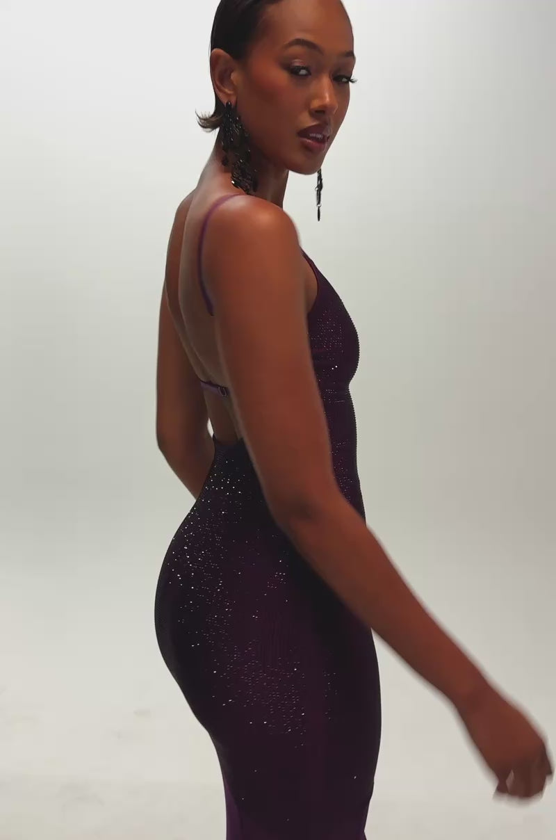 Video of a woman modeling the SHOW A LITTLE LEG RHINESTONE MAXI DRESS IN PLUM—a sleeveless, form-fitting, glamorous evening gown featuring glittery rhinestone accents in a rich plum hue and a sheer lower half.