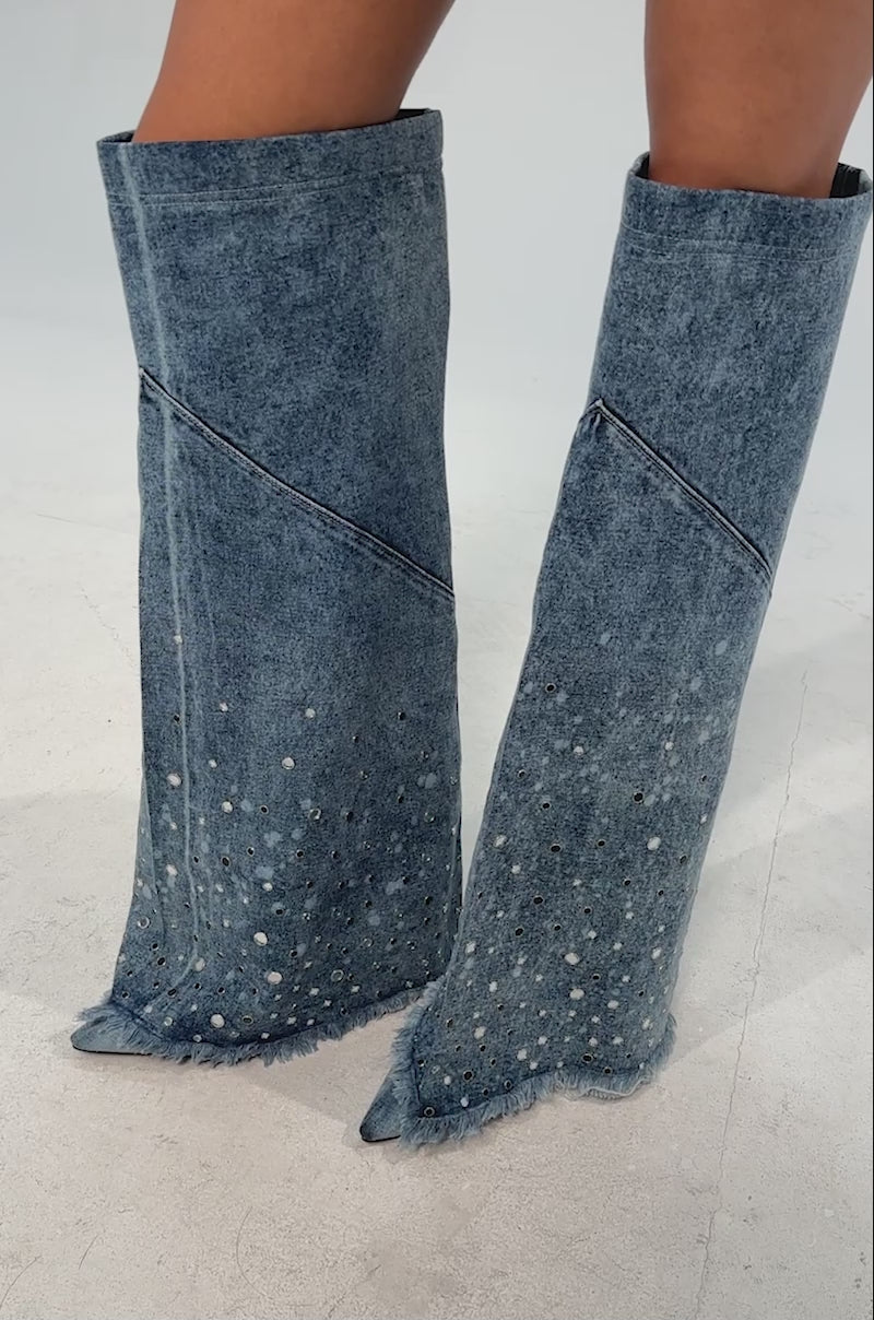 Video of woman modeling the AKIRA WHYNOT DENIM RHINESTONE EMBELLISHED STILETTO BOOT—blue knee-high denim with frayed edges and sparkling rhinestones