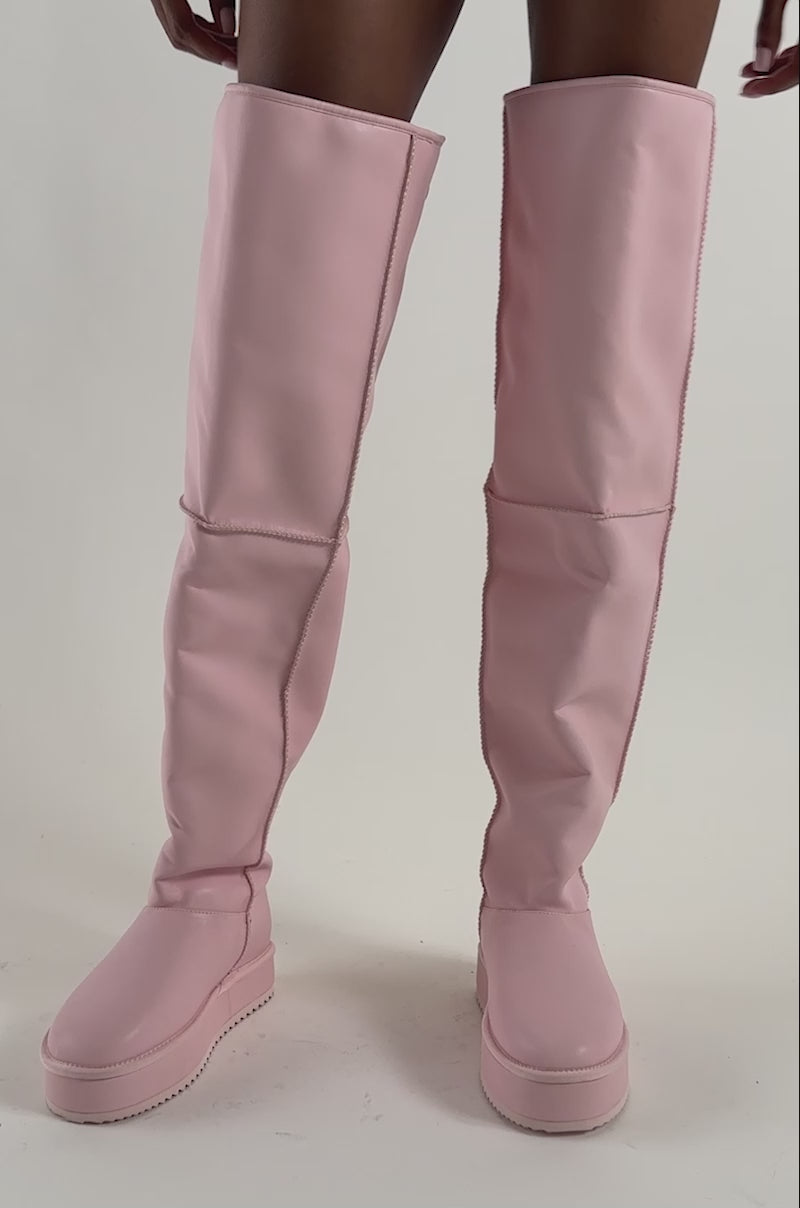 Video of a woman modeling the AZALEA WANG MARLOW Pink PU Sherpa Flatform Boots—knee-high pink faux leather boots with furry cuffs.